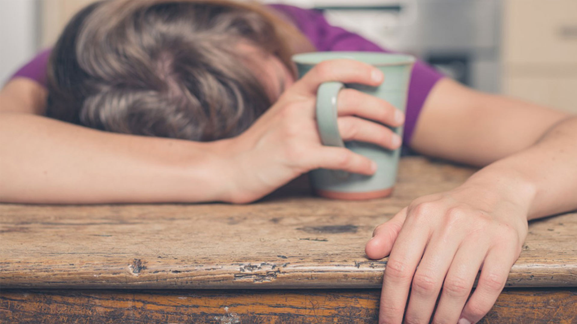 Femme dormant sur la table avec un tasse en main